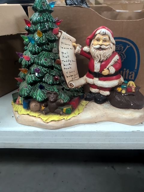 Christmas tree with Santa holding Christmas list and a bag of toys