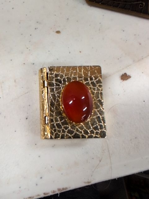 Locket book for necklace with orange gem on top