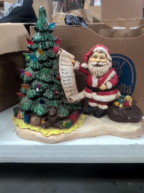 Christmas tree with Santa holding Christmas list and a bag of toys